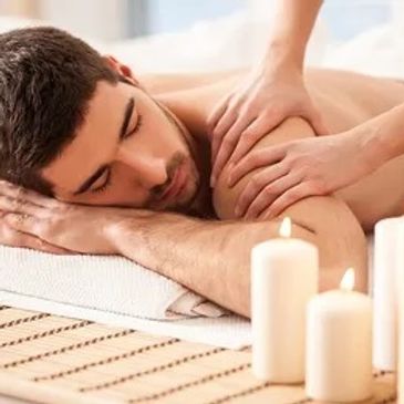 Man receiving a relaxing shoulder massage with lit candles nearby.