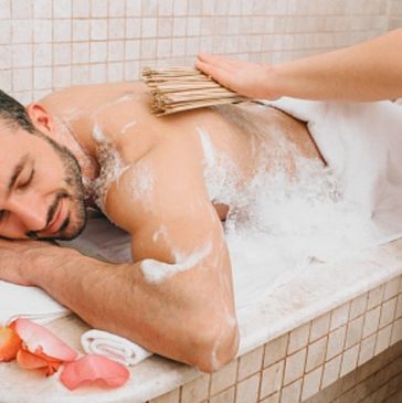 Man enjoying a relaxing back scrub with foam at a spa.