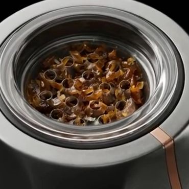 Close-up of a metallic device filled with curled brown shavings.