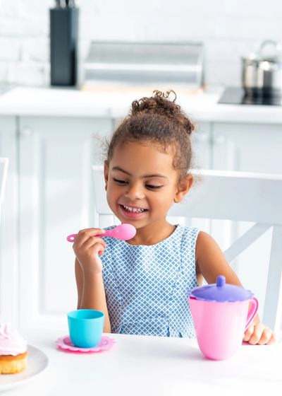 a little girl sitting down with toys on the table