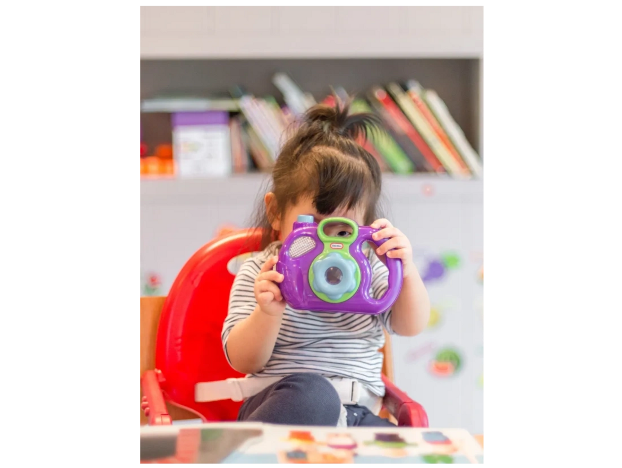 a little girl playing with a toy camera