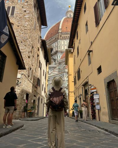 Tourist admiring historic cathedral dome in narrow European street.
