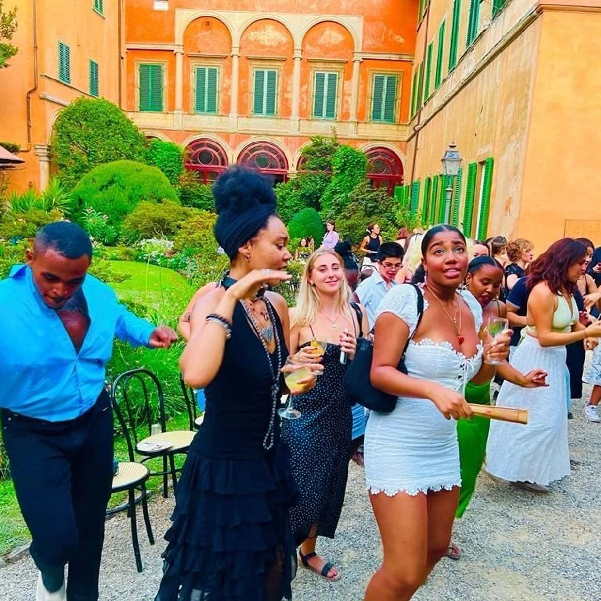 People socializing and dancing outdoors in a garden courtyard.