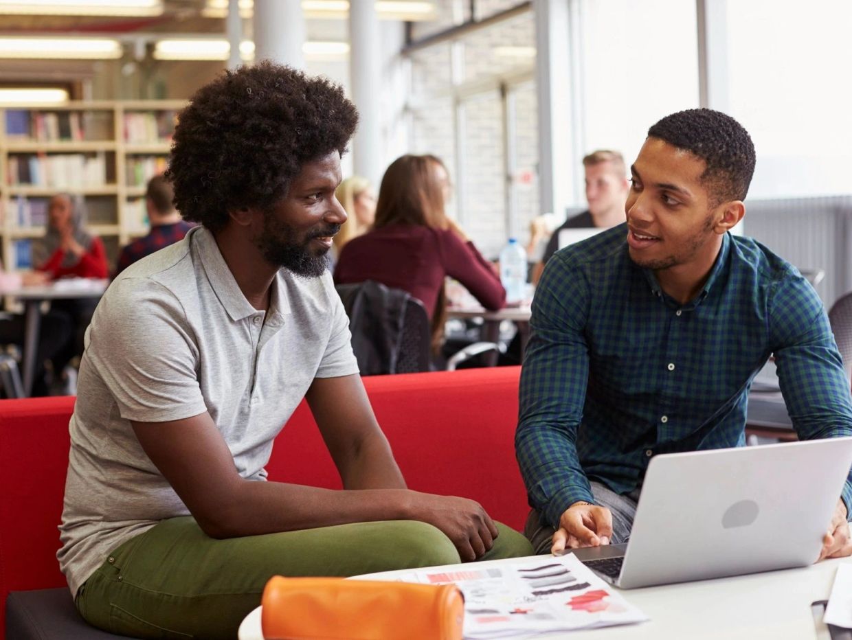 Two men discussing work on a laptop in a casual office.