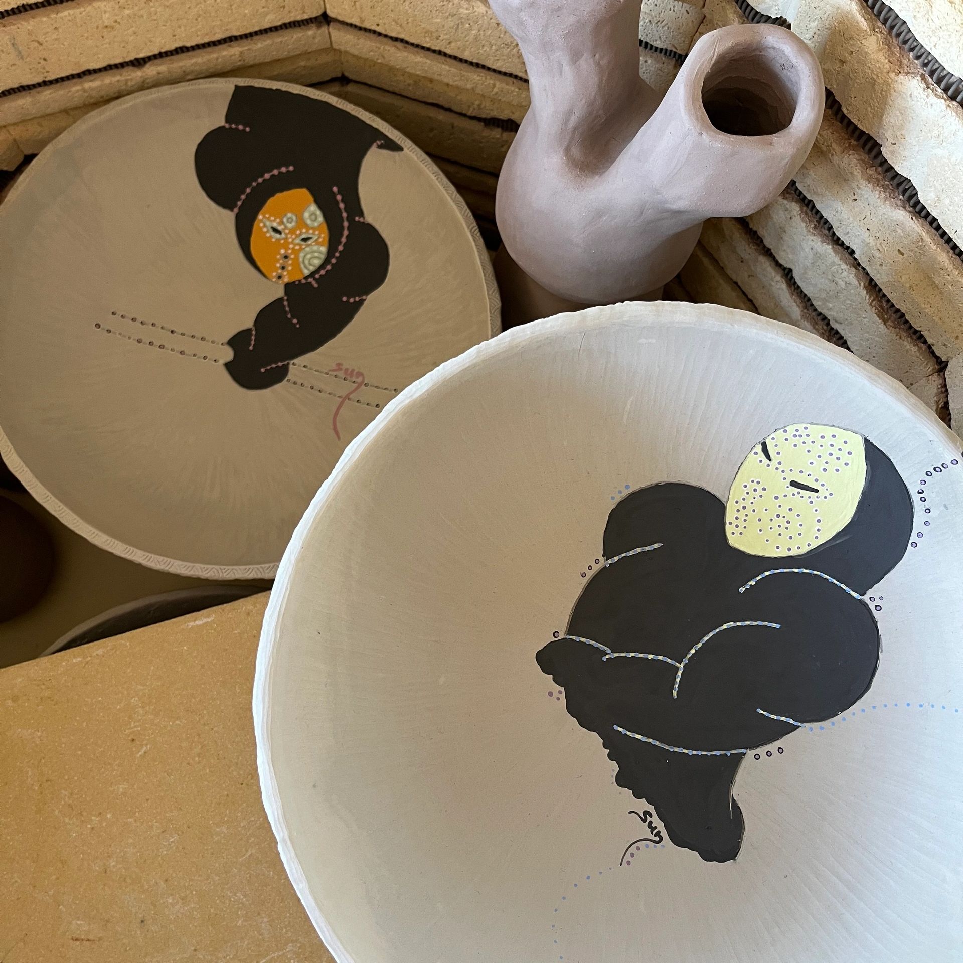 Two large ceramic bowls with underglaze designs painted on them. 