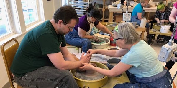 An instructor helping a student with wheelthrowing at Community Kiln