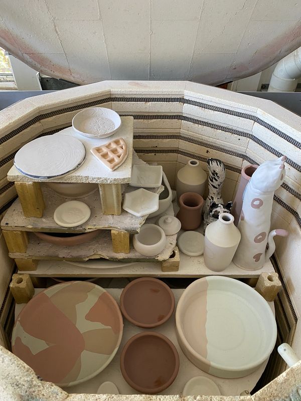 The inside of an unfired glaze kiln that is loaded with student wares.