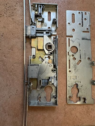 Disassembled metallic lock mechanism parts on a surface.