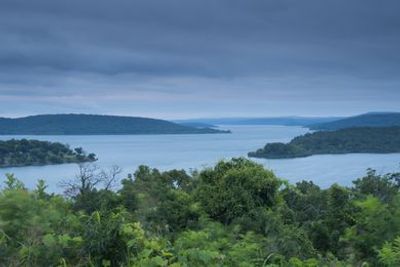 Scenic lake view with lush greenery under a cloudy sky.