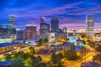 City skyline at dusk with vibrant lights and colorful sky.