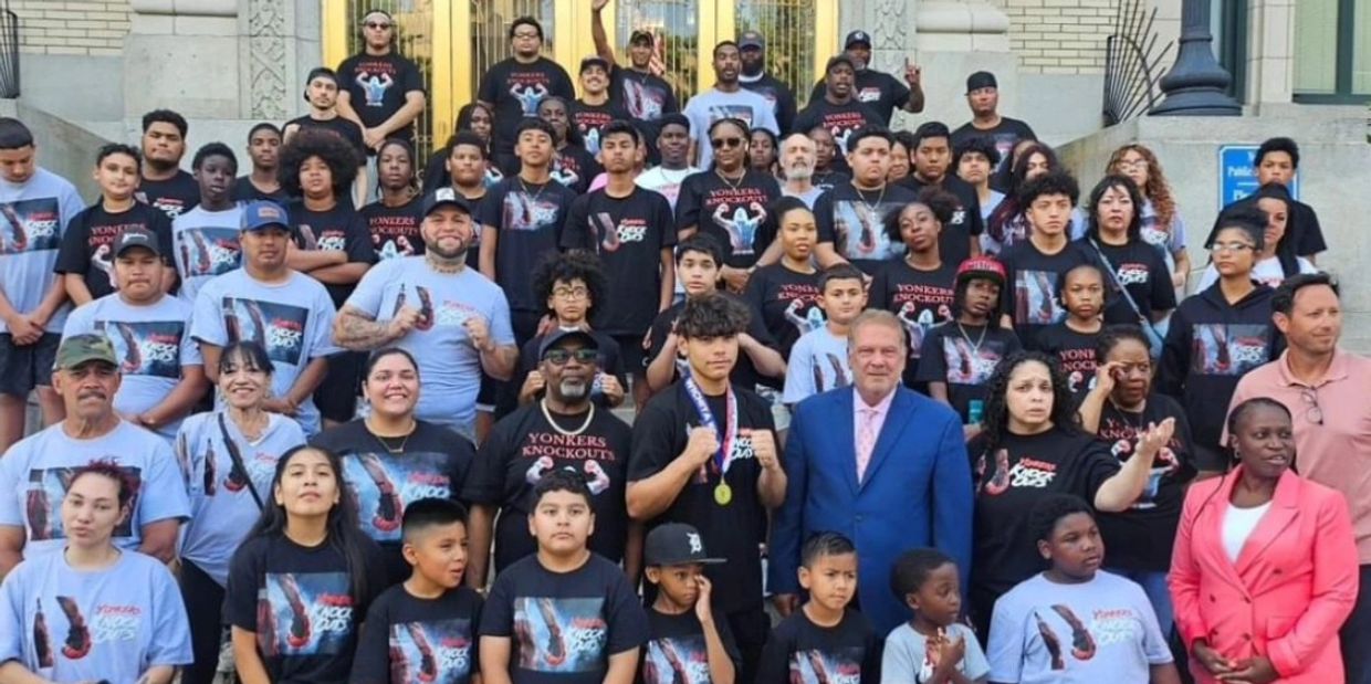Large group wearing matching Yonkers Knockout shirts posing on steps.