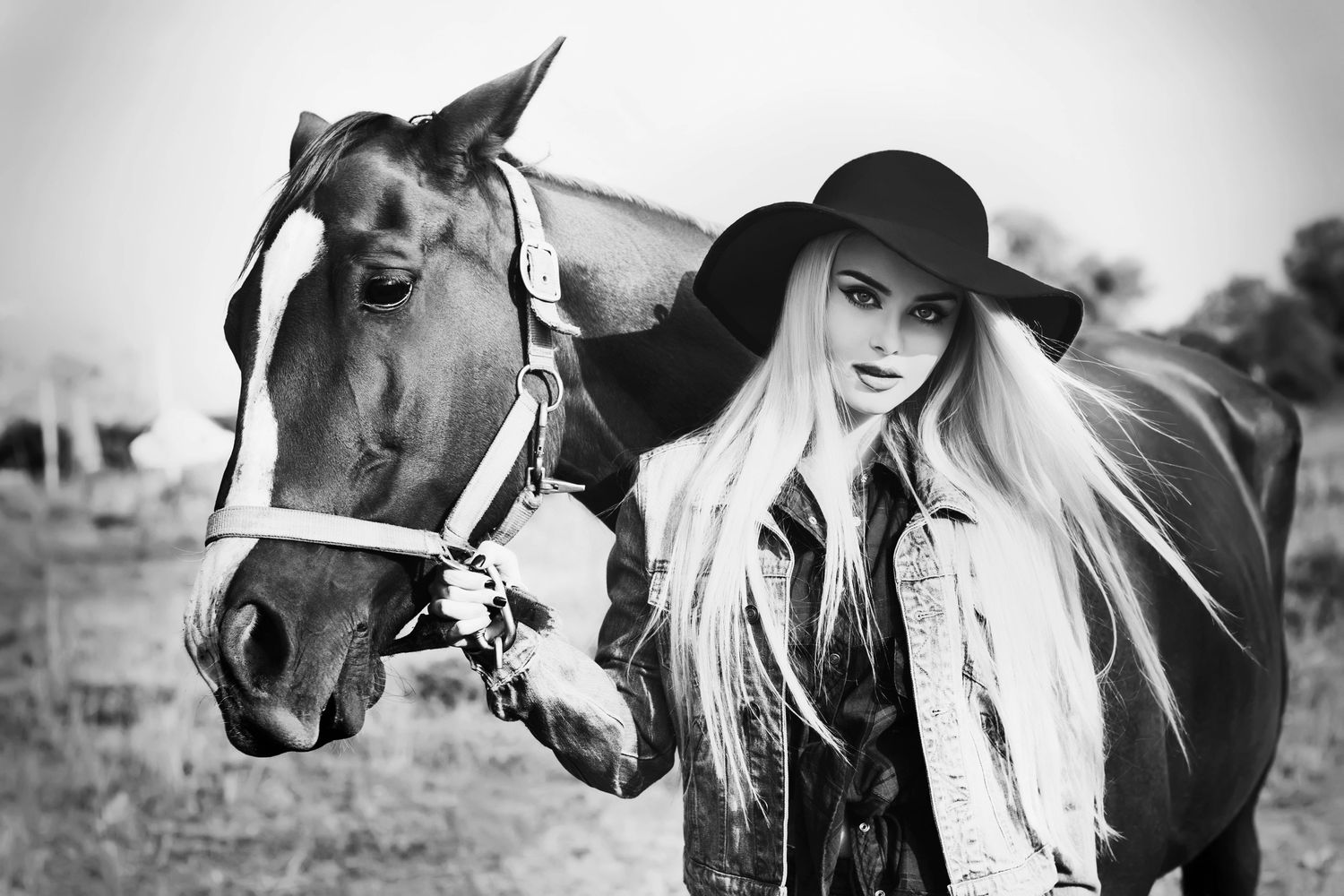 cowgirl with a horse and denim jacket and black hat