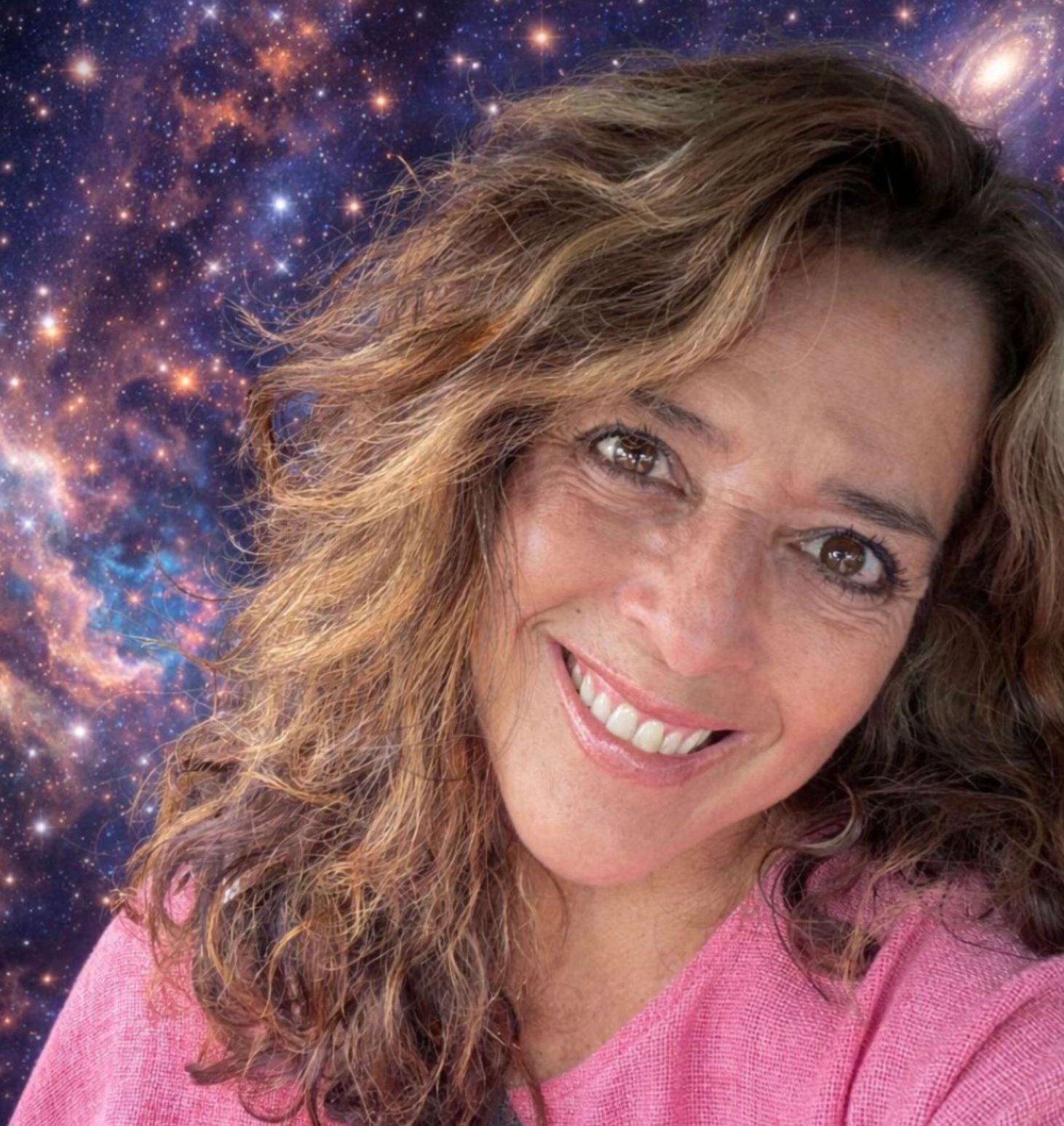 Smiling woman with curly hair against a cosmic galaxy background.