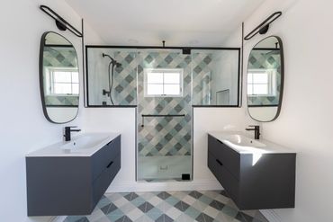 Modern dual-sink bathroom with geometric tiles and black fixtures.