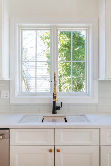 Modern kitchen sink with a black faucet under a bright window.