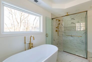 Modern bathroom with freestanding tub and glass-enclosed marble shower.