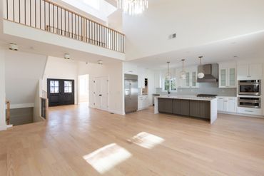 Bright open-concept kitchen and living area with light wood floors and high ceilings.