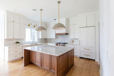 Bright modern kitchen with white cabinets and a wooden island.