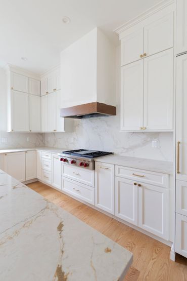 Bright modern kitchen with white cabinets and marble countertops.