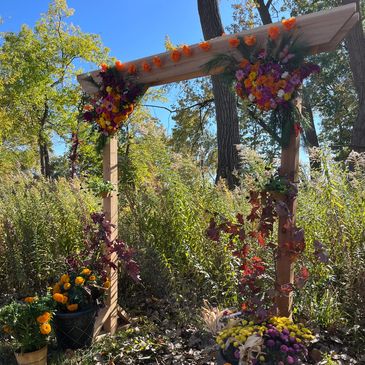 Wooden arch decorated with colorful flowers in a sunny garden.