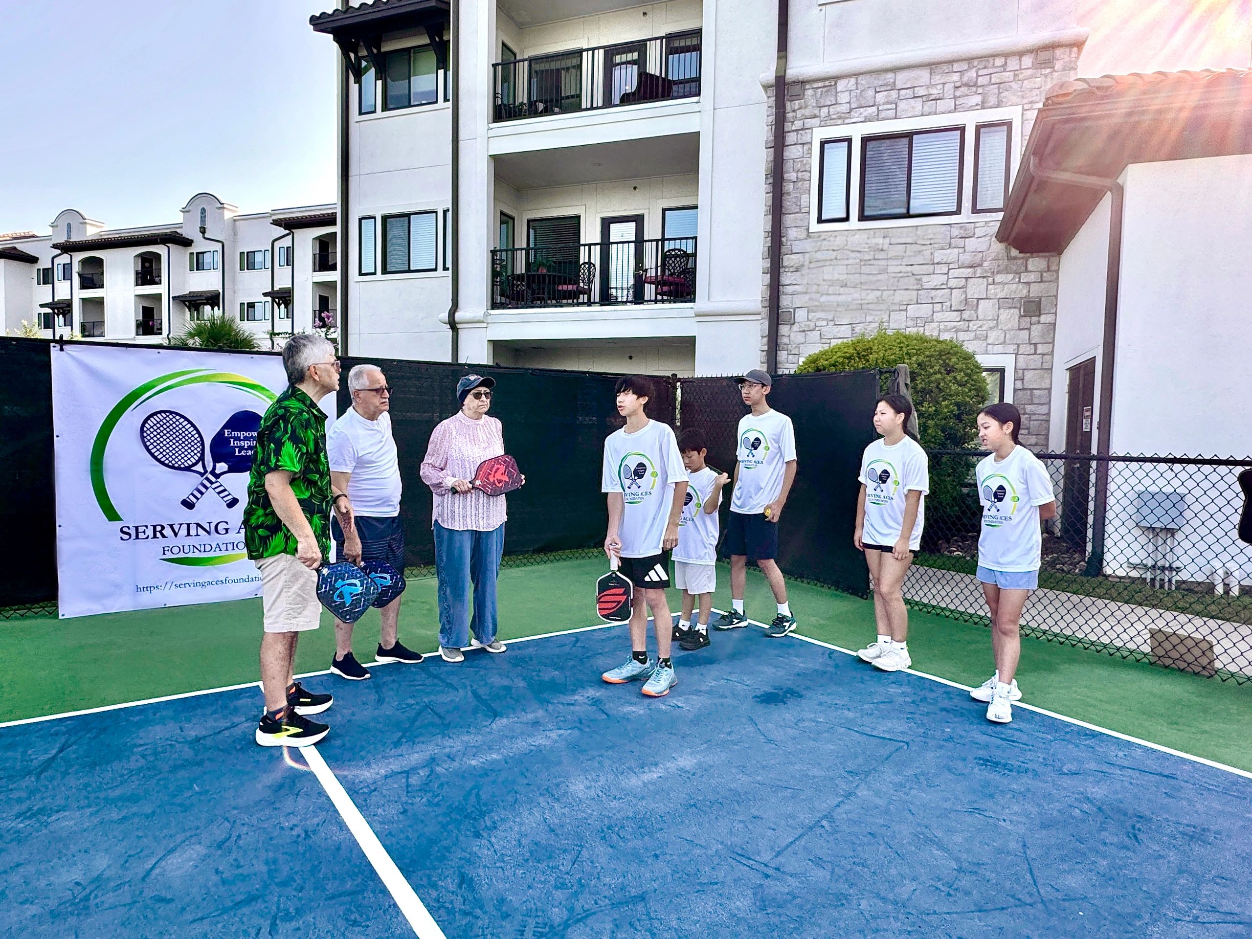 Group of people on a pickleball court with rackets.