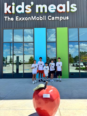 Group of kids in front of colorful 'kids' meals' sign.