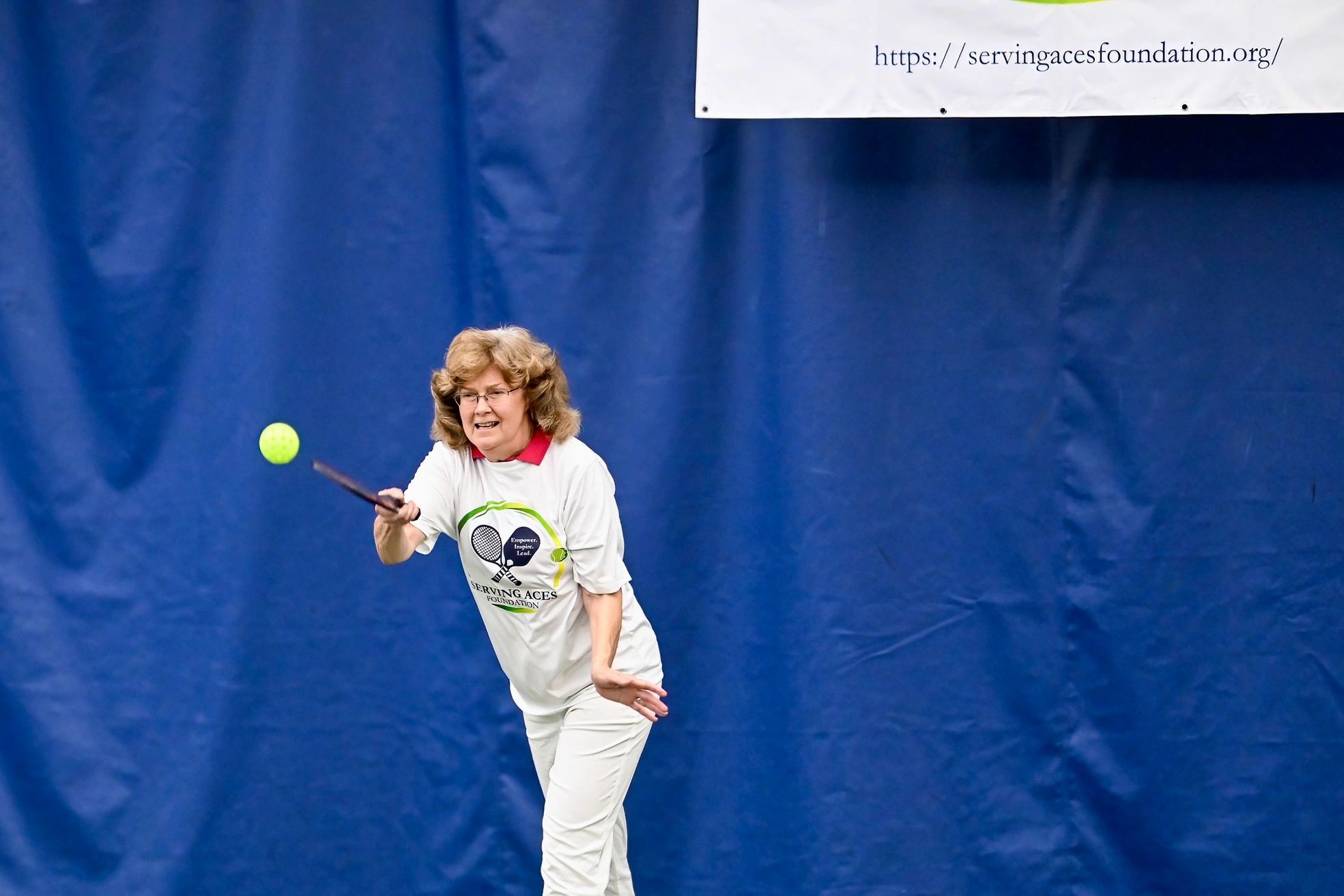 Woman playing pickleball indoors.