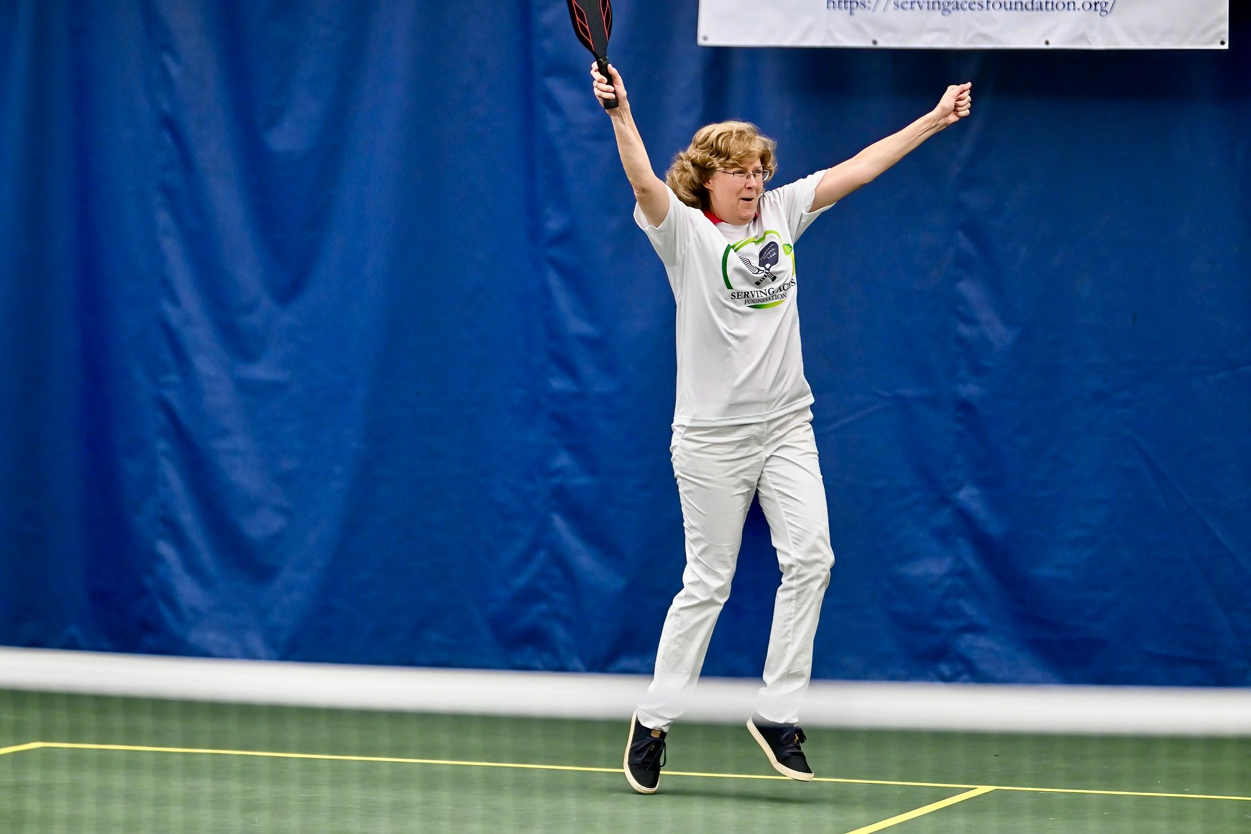 Woman celebrating on a tennis court.