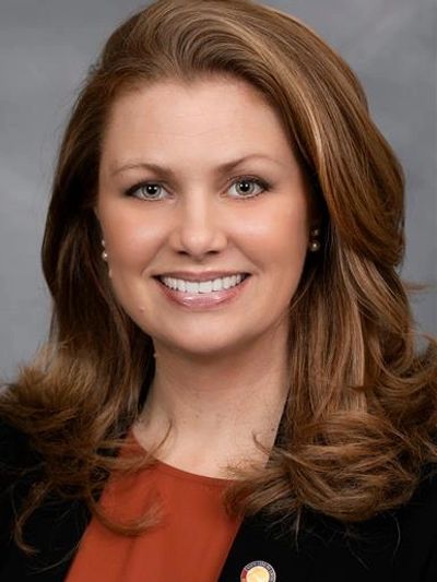 A smiling woman with long brown hair in a professional headshot.