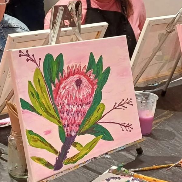 Painting of a pink flower with green leaves on a pink background.