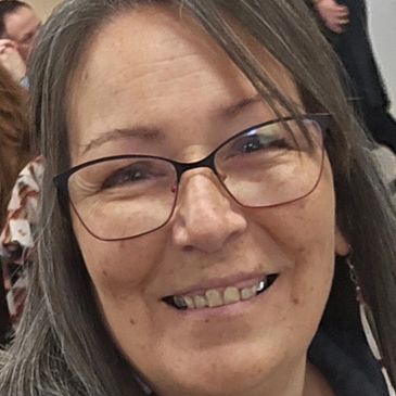 Smiling woman with glasses in a casual indoor setting.