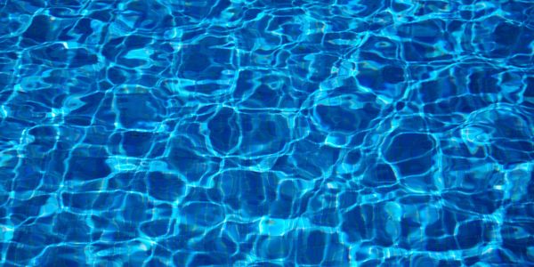 Clear blue water in a swimming pool shimmering under sunlight.