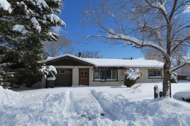 Snow-covered house and yard on a clear winter day.