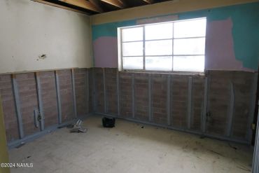 Empty unfinished room with exposed brick and window.