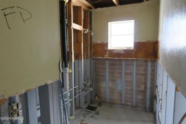 Room under construction with exposed pipes and wall studs.