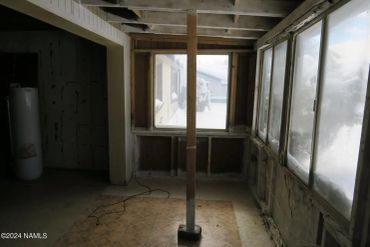 Room with exposed ceiling beams and large windows covered in ice.