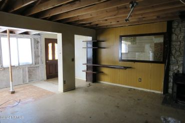 Empty, unfinished room with exposed ceiling beams and wooden shelves.