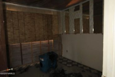 Dark unfinished room with exposed walls and floor fan.