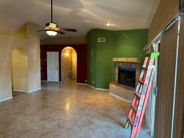 Living room with colorful walls, tiled floor, and a ceiling fan.