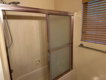 Bathroom shower with frosted sliding doors and wooden blinds.