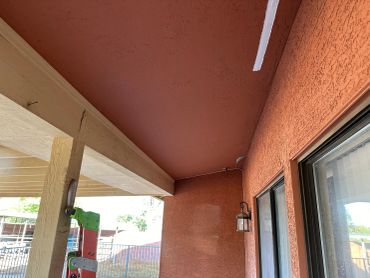View of a porch ceiling and wall with textured paint.