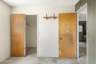 Room with two open wooden doors and a small wall shelf.