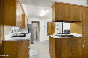 Vintage kitchen with wooden cabinets and white tile countertops.
