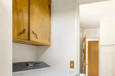 Laundry area with washing machine and wooden cabinet.