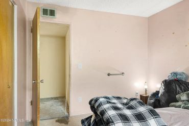 Cluttered bedroom corner with plaid blanket and trash bags.