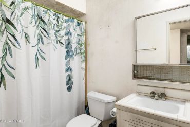 Small bathroom with a floral shower curtain and basic fixtures.