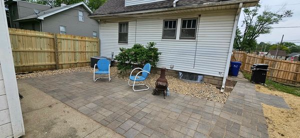Backyard patio with blue chairs and chiminea on gray pavers.