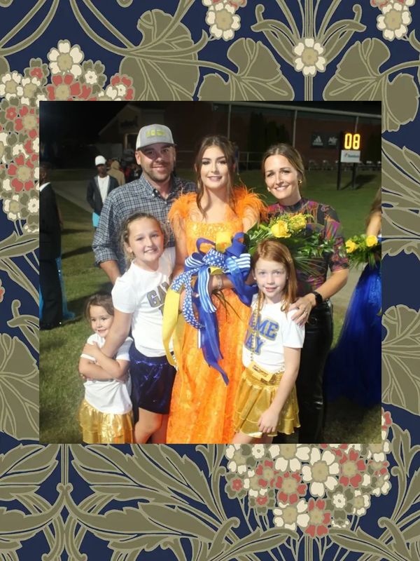 Group photo of a family at an event, girl in orange dress holding ribbon.