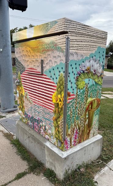 Caja eléctrica decorada con un mural colorido de naturaleza.