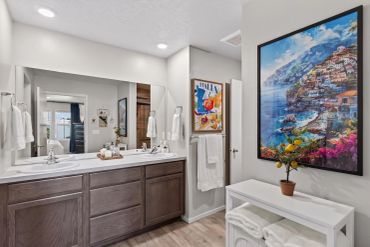 Modern bathroom with dual sinks and vibrant artwork.